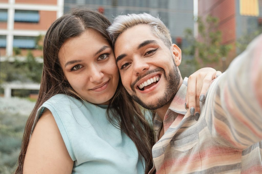 Young diverse friends taking a selfie with mobile phone outdoor - Focus on transgender man face